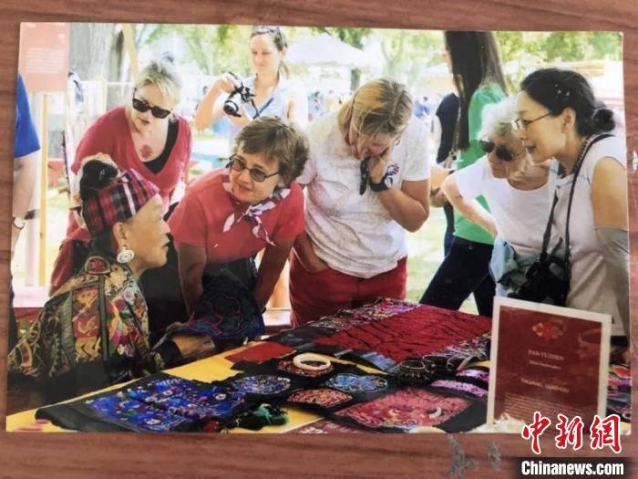 图为潘玉珍老人向外国民众介绍苗绣。 受访者供图